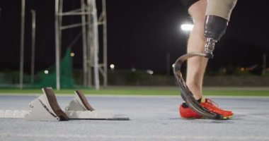 Kafkasyalı engelli erkek sporcunun düşük kesimi koşu yapmaya hazırlanıyor. Spor stadyumunda profesyonel atlet eğitimi.