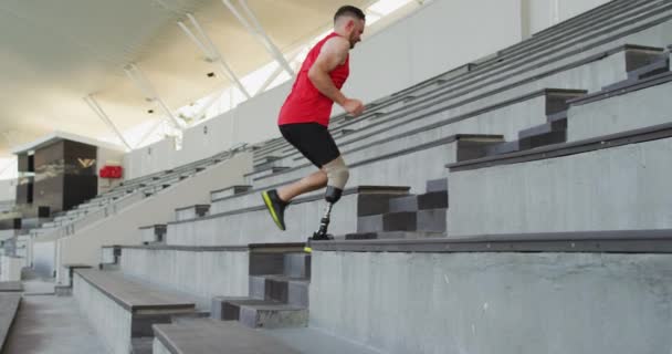 義肢トレーニングを受けた白人障害者の男性アスリートが階段を駆け上がる スポーツ競技場でのプロのランナートレーニング — ストック動画