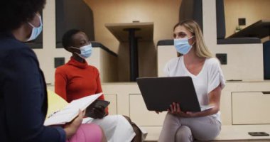 Ofiste yüz maskesi takmış üç farklı bayan ofis arkadaşı birlikte tartışıyorlar. Coronavirus covid 19 salgını sırasında işyerinde hijyen ve sosyal mesafeler.