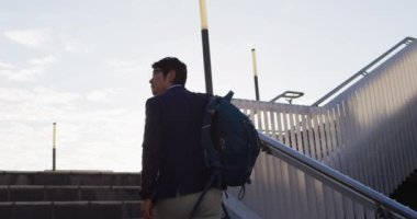 Sırt çantalı Asyalı bir adam şirket parkında merdivenlerden çıkıyor. iş ve yaşam tarzı kavramı