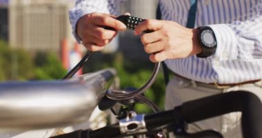 Asyalı adamın bisikletini şirket parkına kilitlemesinin orta bölümü. iş ve yaşam tarzı kavramı