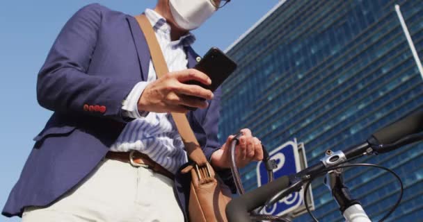 Ασιάτης Που Φοράει Μάσκα Προσώπου Χρησιμοποιώντας Smartphone Ενώ Κλειδώνει Ποδήλατό — Αρχείο Βίντεο