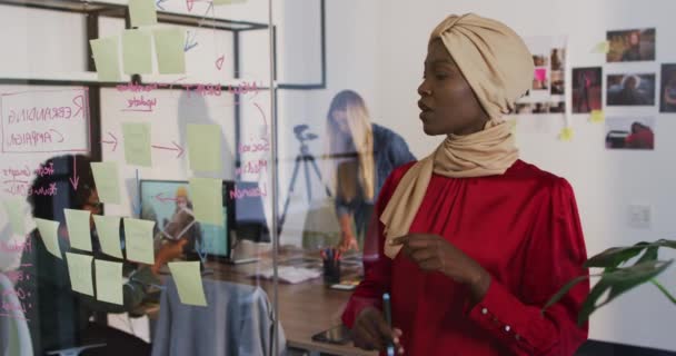 Afroamerikanische Geschäftsfrau Gespräch Mit Kollegen Und Bewegende Notizen Einer Glaswand — Stockvideo