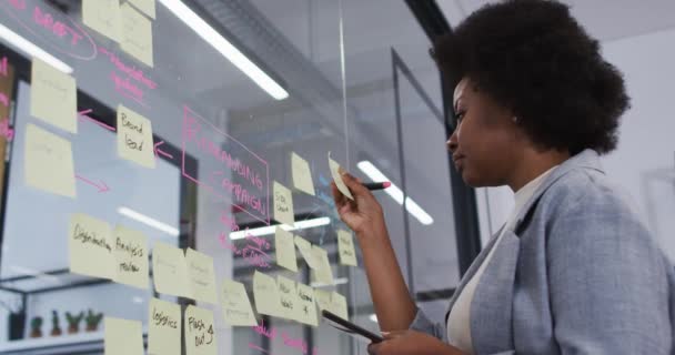 Sonriente Mujer Negocios Afroamericana Lluvia Ideas Utilizando Notas Pared Cristal — Vídeo de stock