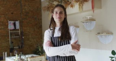 Çapraz elli, çizgili önlük giymiş kameraya bakan gülümseyen beyaz garson. Küçük bağımsız kafe işletmesi.