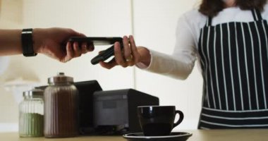Kafkasyalı müşterilerin orta kesiminde, ödeme terminalindeki garsonlara fatura ödemek için akıllı telefon kullanılıyor. Küçük bağımsız kafe işletmesi.