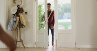 Afro-Amerikan oğlunuz mutlu bir şekilde karşılıyor ve babanızın eve gelişini kucaklıyor. Karantina süresince evde tecrit altında kalmak.