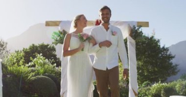 Mihrapta açık havada yürüyen mutlu beyaz bir çiftin portresi. romantik yaz düğünü açık havada.