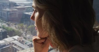 Kafkasyalı iş kadınının profili pencereden bakıyor ve düşünüyor. Modern bir ofiste bağımsız yaratıcı iş.