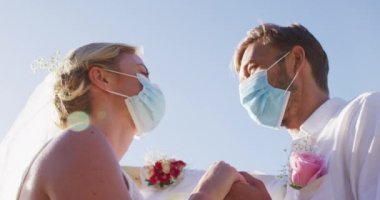 Yeni evlenmiş mutlu beyaz çift portresi mihrapta birbirine dokunuyor, yüz maskeleri takıyorlar. Romantik yaz düğünü Coronavirüs covid 19 salgını.