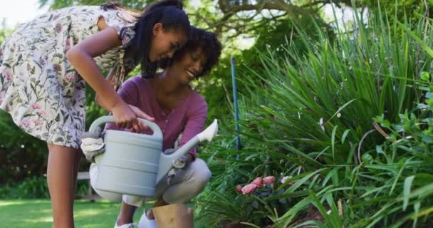 屋外で植物の世話をし 幸せなアフリカ系アメリカ人の母親と娘 隔離中は庭に隔離され — ストック動画