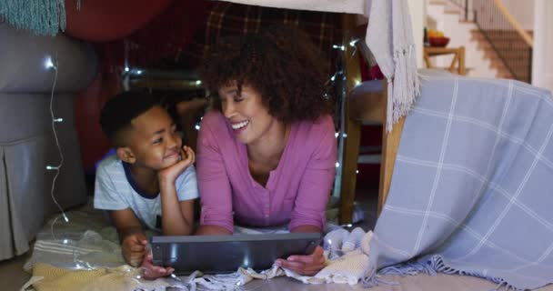 快乐的非洲裔美国母亲和儿子躺在用毛毯做的房子里 用平板电脑 隔离检疫期间单独呆在家里 — 图库视频影像