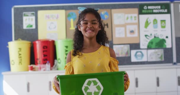 混血的女学生笑着 拿着回收箱 站在教室里 夏天上小学的儿童 — 图库视频影像