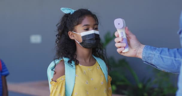 Diverse Male Teacher Measuring Temperature Schoolchildren All Wearing Face Masks — Stock Video