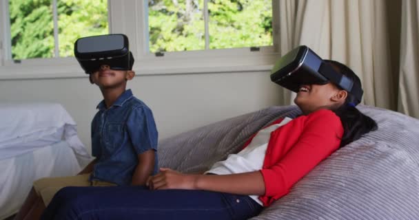 快乐的非洲裔美国儿女坐在沙发上 戴着一副虚拟现实的眼镜 隔离检疫期间单独呆在家里 — 图库视频影像