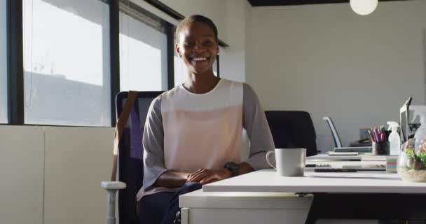 幸せなアフリカ系アメリカ人の実業家が机の上に座り 仕事で笑っている 現代のオフィスで独立した創造的なビジネスを — ストック動画