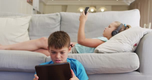 Portrait Caucasian Brother Sister Lying Sofa Using Tablet Smartphone Staying — Stock Video