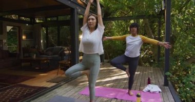 Asyalı anne ve kız bahçede yoga yapıyorlar. Karantina süresince evde tecrit altında..