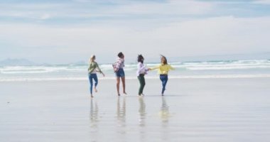 Bir grup mutlu bayan arkadaş sahilde koşup eğleniyorlar. Tatil, özgürlük ve boş zaman.