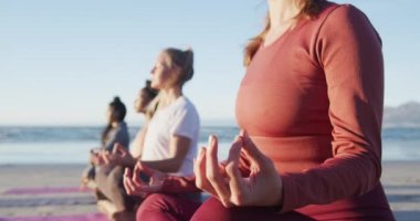 Bir grup farklı bayan arkadaş sahilde meditasyon yapıyor. sağlıklı aktif yaşam tarzı, açık hava uygunluğu ve refahı.