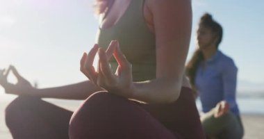 Bir grup farklı bayan arkadaş sahilde meditasyon yapıyor. sağlıklı aktif yaşam tarzı, açık hava uygunluğu ve refahı.