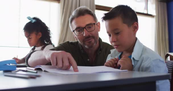 Diverso Maestro Masculino Ayudando Escolar Sentado Aula Lectura Ejercicio Niños — Vídeos de Stock