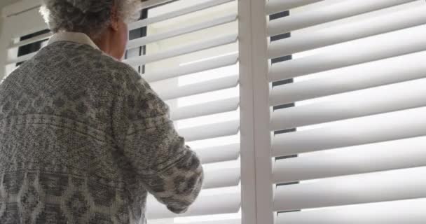 非洲裔美国老年妇女从窗口往外看的后视镜 退休老人生活方式隔离隔离观念 — 图库视频影像