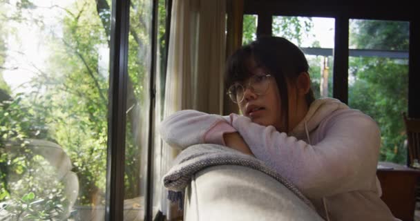 Asiatisches Mädchen Das Durchs Fenster Schaut Und Auf Dem Sofa — Stockvideo