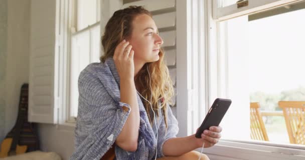 Mulher Caucasiana Feliz Usando Fones Ouvido Sentado Usando Smartphone Sala — Vídeo de Stock