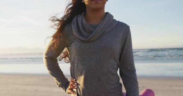 在海滩上拿着瑜伽垫的混血女子的画像 积极的生活方式 户外运动和幸福 — 图库视频影像