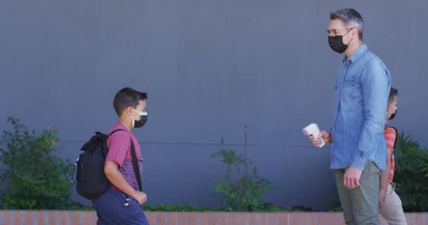 Profesor Masculino Diverso Midiendo Temperatura Del Colegial Todos Usando Máscaras — Vídeo de stock