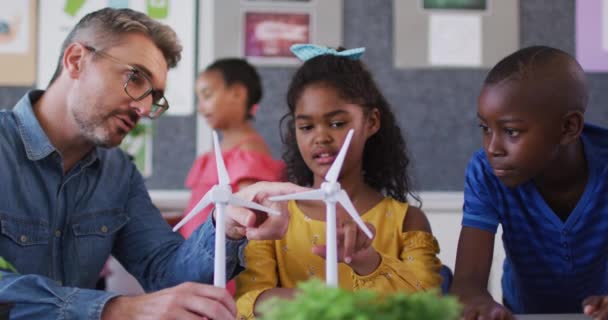 風力発電と再生可能エネルギーの源について学ぶ 多様な男性教師と子供 小学校の子どもたちは — ストック動画
