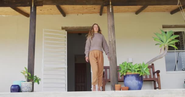 笑着站着的高加索女人 靠着外面的房子从阳台往外看 健康的生活 接近大自然在离网的农村家庭 — 图库视频影像
