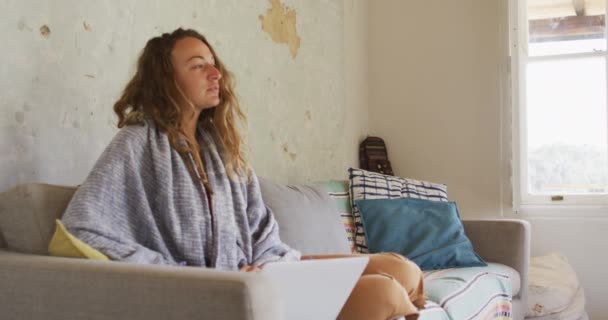 Thoughtful Caucasian Woman Wearing Blanket Sitting Sofa Using Laptop Sunny — Stock Video