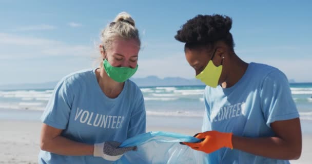 Дві Різноманітні Жінки Волонтерських Футболках Масках Обличчя Збирають Сміття Пляжу — стокове відео