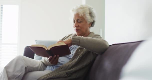 Afroamerikansk Äldre Kvinna Läser Bok När Hon Sitter Soffan Hemma — Stockvideo