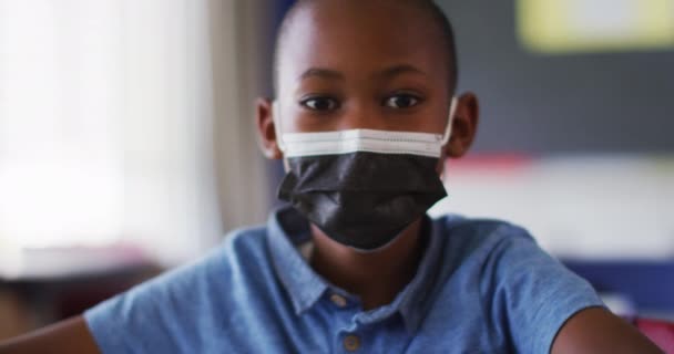 Retrato Colegial Afroamericano Usando Mascarilla Sentado Aula Mirando Cámara Niños — Vídeos de Stock