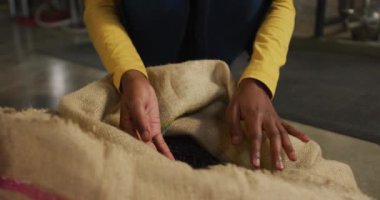 Cin imalathanesinde çalışan Afrikalı Amerikalı bir kadının elleri çuvaldaki ardıç meyvelerini inceliyor. Bağımsız bir içki imalathanesinde çalışıyorum..