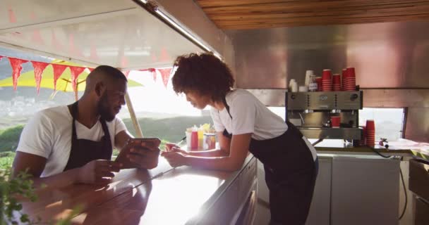 非洲裔美国人夫妇穿着使用数字平板电脑的围裙 并在餐车上做笔记 食品卡车和街头食品概念 — 图库视频影像