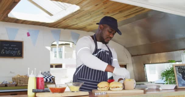 Potret African American Man Mengenakan Apron Tersenyum Sambil Menyiapkan Burger — Stok Video