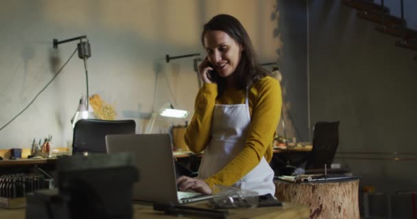 Kaukasische Juwelierin Der Werkstatt Mit Schürze Schreibtisch Sitzend Mit Laptop — Stockvideo