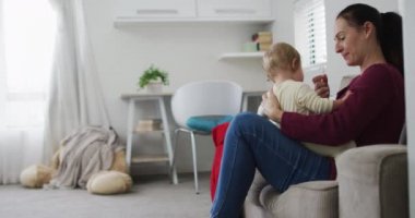 Beyaz bir anne bebeğiyle evde kanepede otururken düdük çalıyor. annelik, sevgi ve çocuk bakımı kavramı