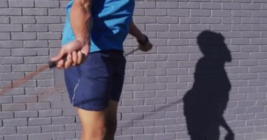 Formda Afro-Amerikan bir adam şehirde egzersiz yapıyor, sokakta ip atlayarak atlıyor. fitness ve aktif şehir dışı yaşam tarzı.