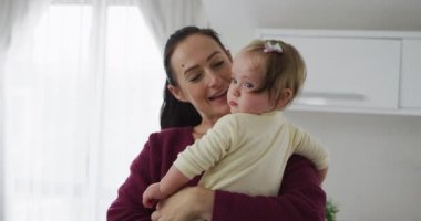 Beyaz bir anne bebeğini kucağında tutarken oynayıp öpüşüyor. annelik, sevgi ve çocuk bakımı kavramı