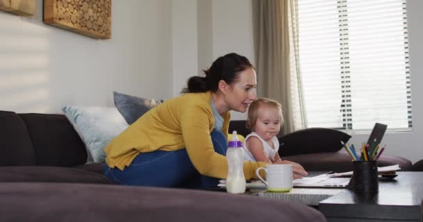 Caucasian Mother Holding Her Baby Using Laptop Taking Notes While — Vídeos de Stock