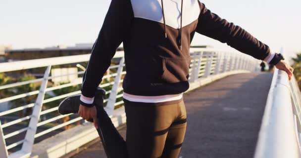 African American Man Wearing Earphones Exercising Outdoors Standing Footbridge Stretching — Vídeo de stock