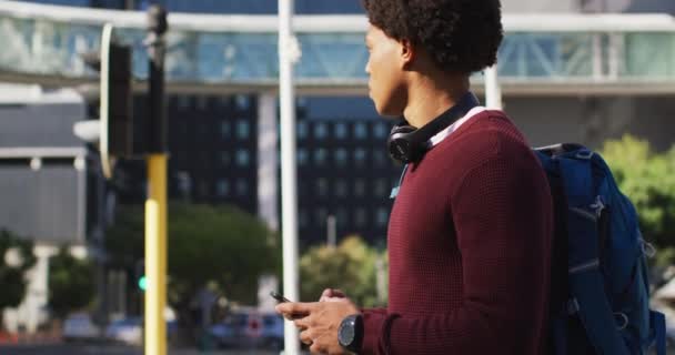 Homem Afro Americano Cidade Usando Smartphone Usando Fones Ouvido Mochila — Vídeo de Stock