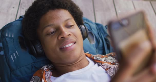 Homem Americano Africano Sorridente Cidade Deitado Convés Usando Fones Ouvido — Vídeo de Stock