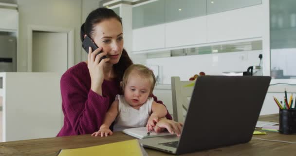 Caucasian Mother Holding Her Baby Talking Smartphone Using Laptop While — Vídeos de Stock