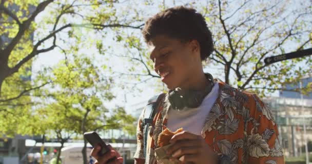 Şehirdeki Mutlu Afro Amerikan Adam Akıllı Telefon Kullanıyor Kulaklık Takıyor — Stok video